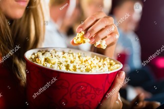 stock-photo-woman-eating-large-container-of-popcorn-in-cinema-or-movie-theater-126127955.jpg