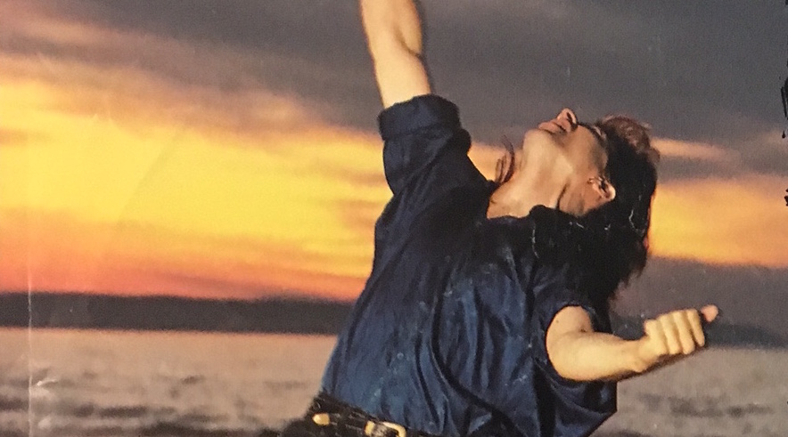 Gowan with his head flung back, doing a dance on the beach at sundown