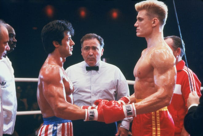 Stallone (Rocky) and Lundgren as Ivan Drago, shake hands before the bout with referee in middle surrounded by their coaches