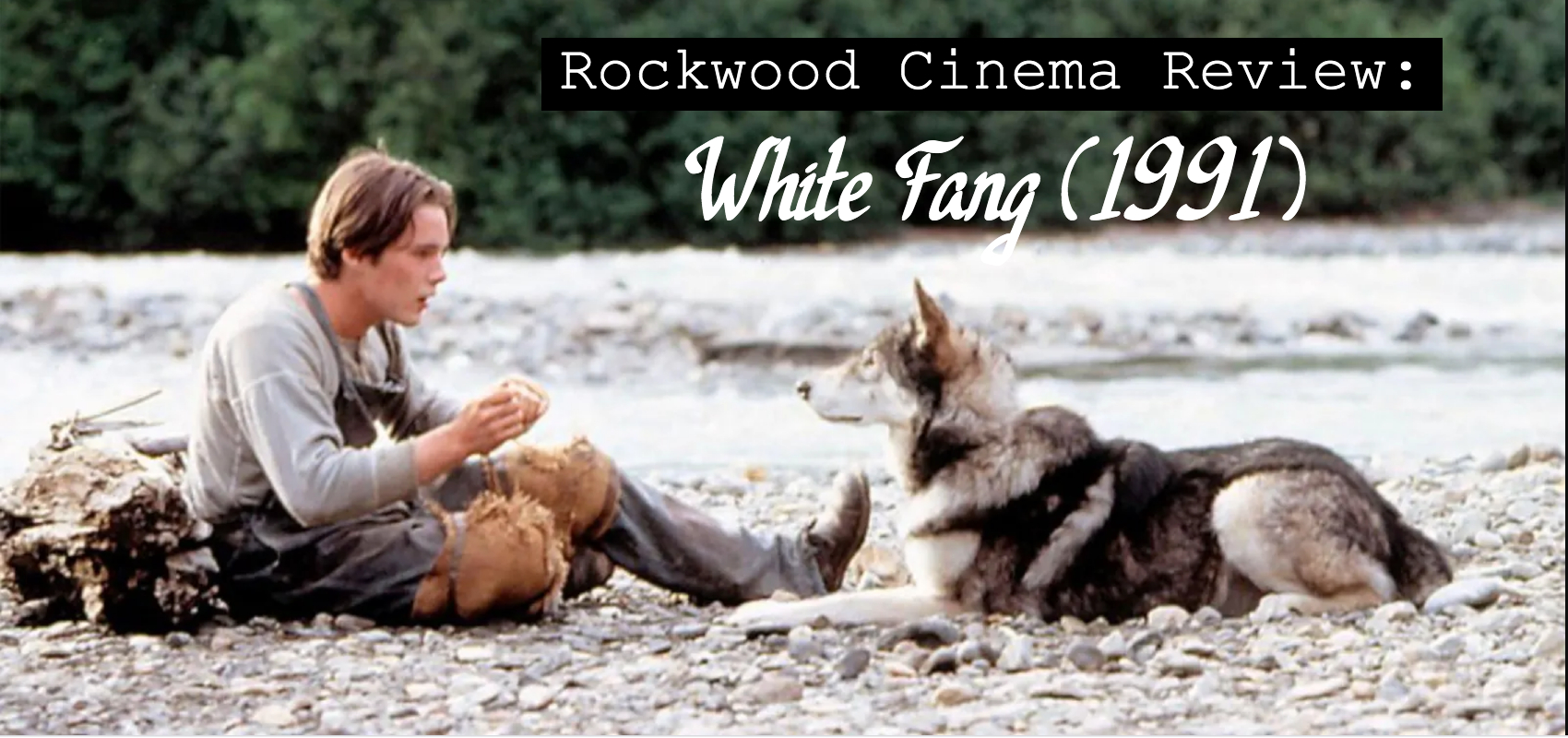 Scene from White Fang where Ethane Hawke sits holding food in his hand. A husky mix dog sitting near him looks attentively.