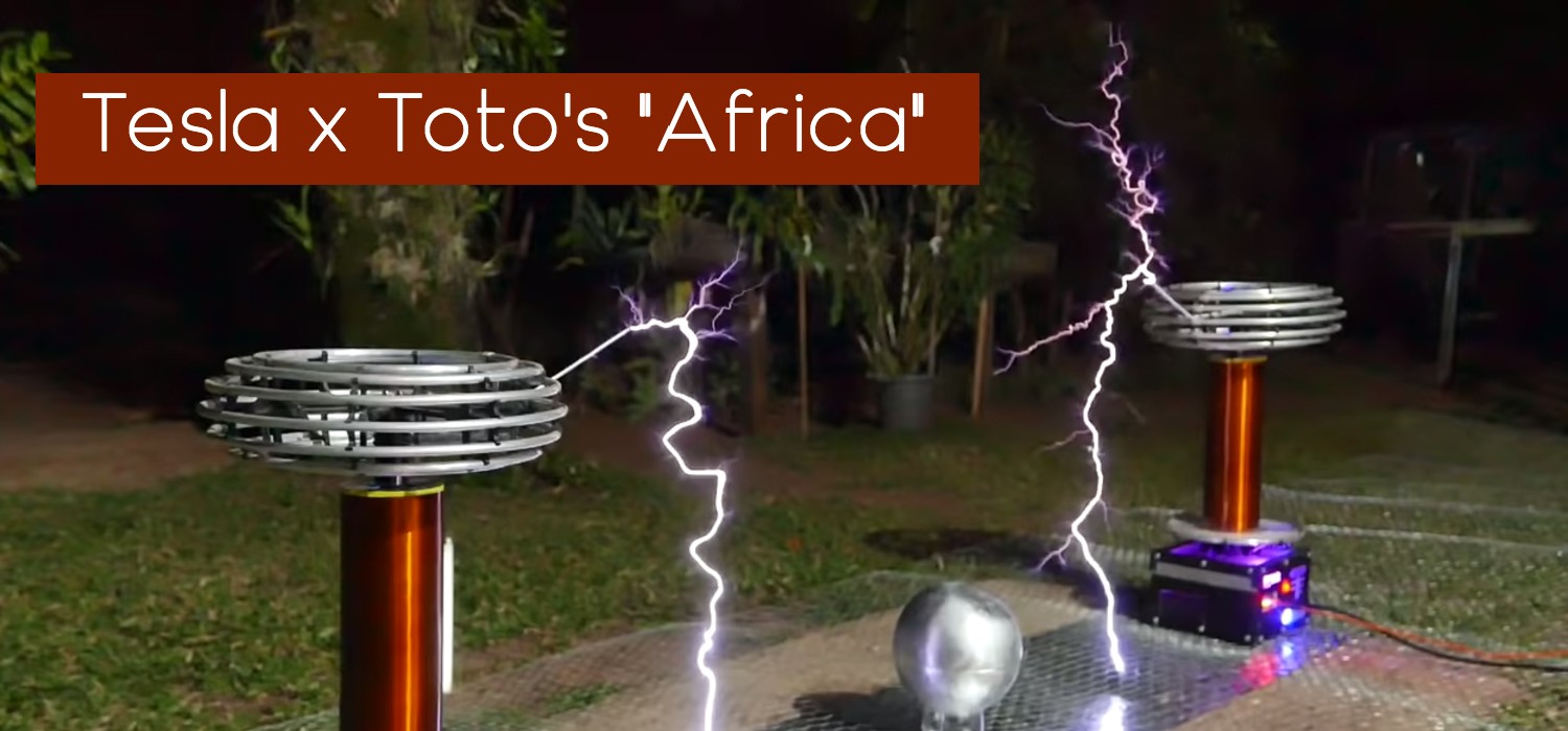 Two red Tesla coils spark with an arching current of electricity touching the metal floor between them