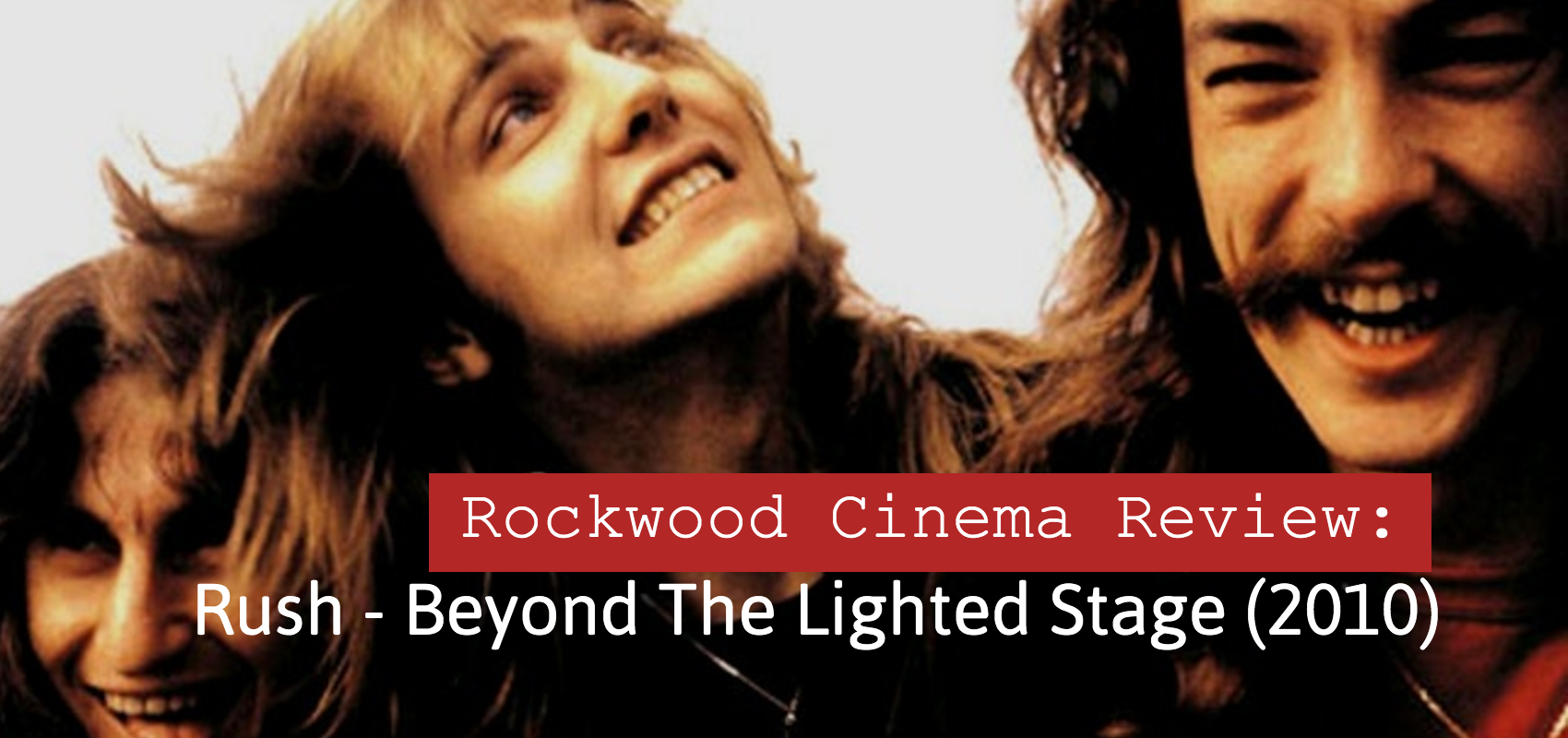 Rush (Geddy Lee, Alex Lifeson and Neil Peart) taken from the 70s with long hair laughing.